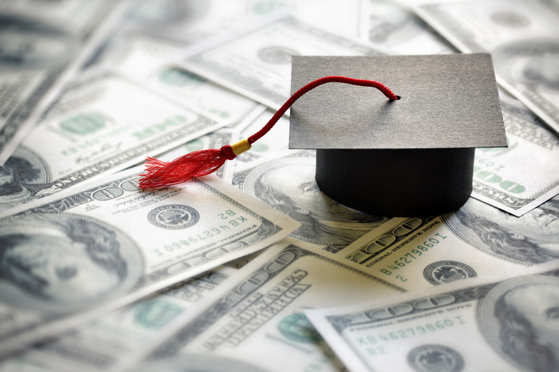 Graduation cap on top of a spread of dollar bills.